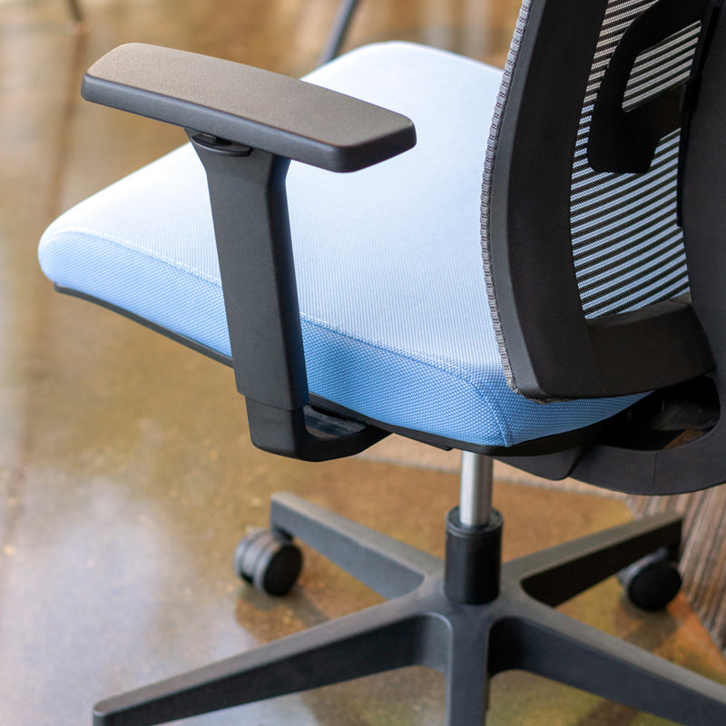 Close up view of fabric on ergonomic task chair with grey mesh back and blue fabric seat.