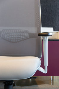 Close up view of ergonomic task chair with grey mesh back and grey fabric seat, adjustable arm rests and lumbar support.