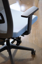 Load image into Gallery viewer, Close up view showing height adjustments for ergonomic task chair with grey mesh back and blue fabric seat.

