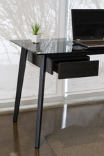 Load image into Gallery viewer, Close up of smoke glass desk with metal legs and black side drawer.
