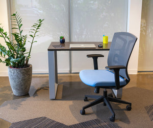 Loop Leg desk with laptop and notebook on surface. A grey and blue office chair sits in front.