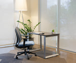Load image into Gallery viewer, Loop leg desk with a laptop on surface and a grey and blue office chair
