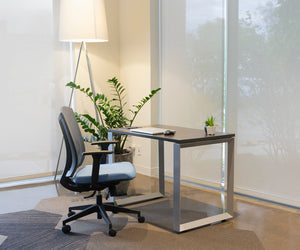 Loop leg desk with a laptop on surface and a grey and blue office chair