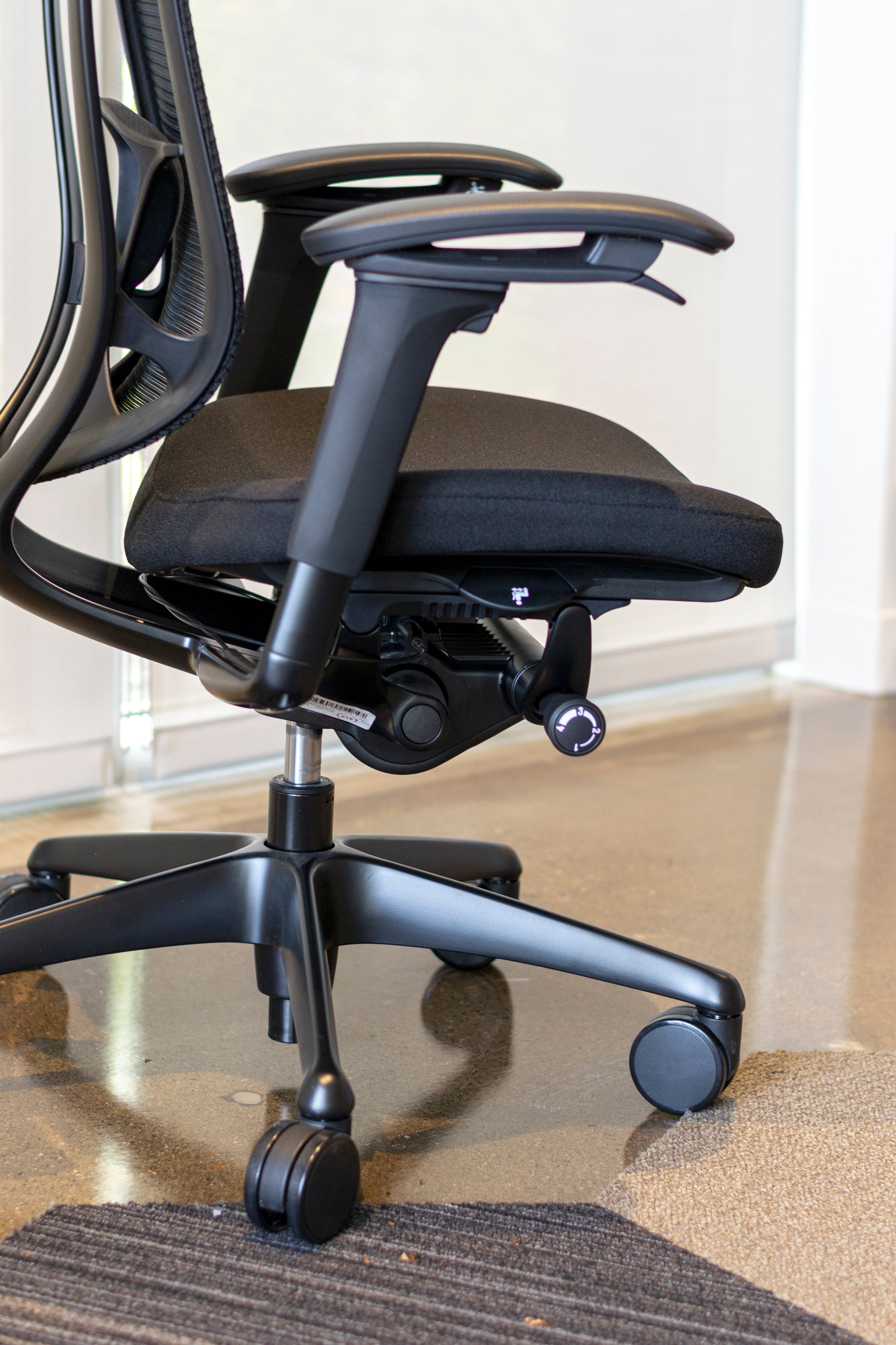Side view of black Nuova work chair showing multiple adjustment levers located at fingertips.