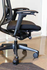 Load image into Gallery viewer, Side view of black Nuova work chair showing multiple adjustment levers located at fingertips.
